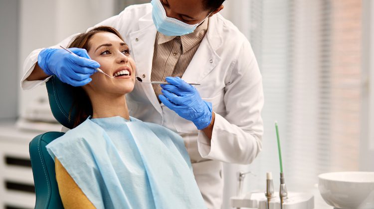 Dentist examining a smiling patient in a clinic.